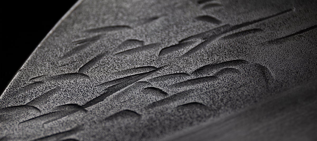 Macro close-up of the hand-forged hammered carbon steel finish